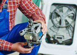 Washing machine repair. Repairer hands with electric engine motor in front of damaged unit